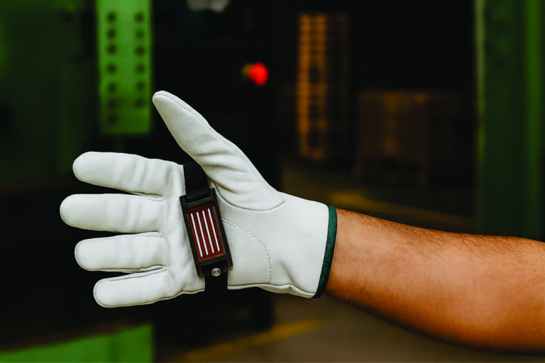 Operador usando luva de segurança com pulseira magnética para chapas em ambiente industrial.